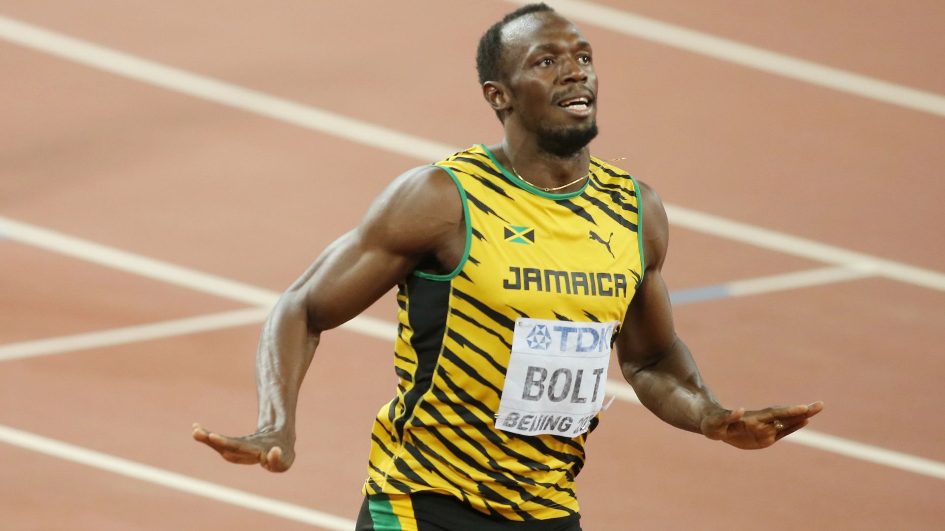 Usain Bolt crossing the finish line during a sprint race, wearing a Jamaican uniform with yellow and green stripes, at a major competition.